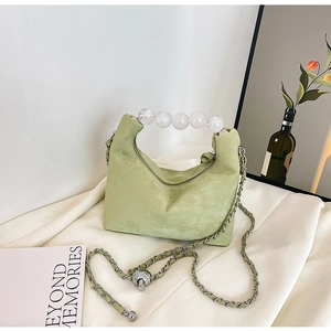 Detail of light green crescent handbag featuring a unique transparent beaded handle and chain