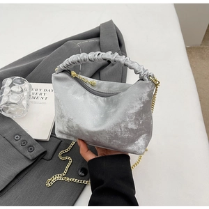 Macro detail of luxury grey velvet pleated handbag with gold chain and marble finish