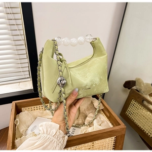 Detail of light green velvet handbag with transparent beaded handle and silver chain