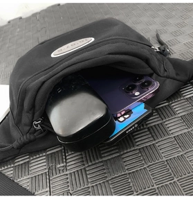 Détail du compartiment principal du sac de poitrine sport contenant un smartphone noir