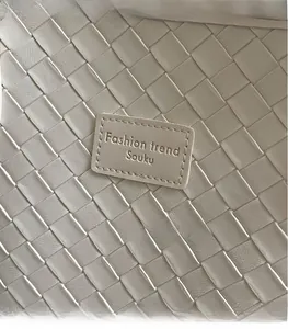 Close-up of cream woven leather tote showing diamond texture and brand logo detail