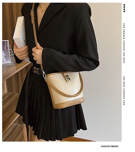 Beige and brown leather bucket bag detail with silver turn-lock clasp and shoulder strap