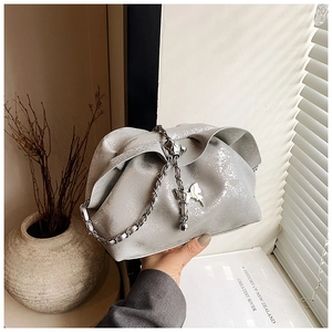 Close-up of metallic silver pleated cloud bag with silver chain and butterfly charm