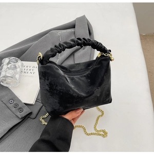 Close-up of black pleated cloud handle bag with golden chain and textured fabric