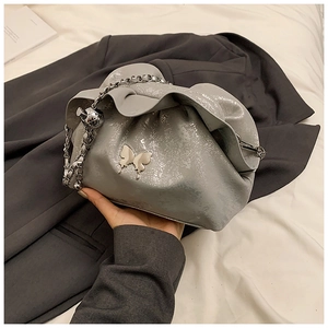 Detail of grey pleated cloud bag with silver butterfly charm and chain strap