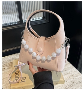 Close-up of pink leather crossbody bag featuring a distinctive white beaded handle