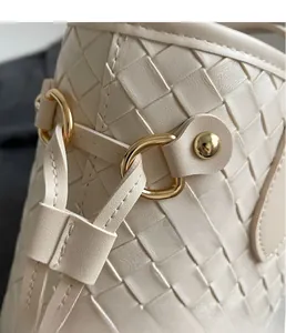 Detailed close-up of premium cream woven leather texture and a polished gold metal buckle