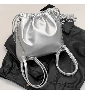 Detail of metallic silver drawstring backpack with adjustable chain straps and bow accent