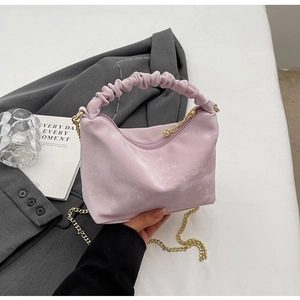 Detail of light pink pleated handbag featuring elegant gold metal chain strap