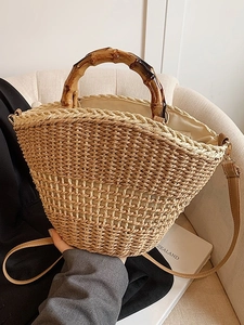 French retro straw handbag with bamboo handles and crossbody strap on a white chair