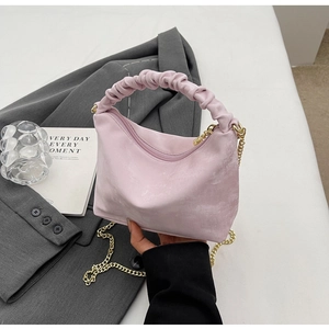 Close-up of pink pleated cloud bag featuring scrunchie handle and gold chain strap