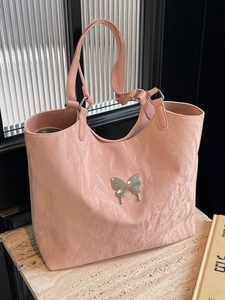 Pink oversized tote bag with bow detail and metallic butterfly ornament for women