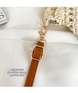 Detail of adjustable brown leather shoulder strap with gold metal lobster clasp on woven bag