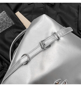 Close-up of a silver metallic drawstring bucket bag with buckle strap and logo detail