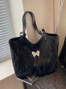 Black crinkled leather tote bag with silver butterfly charm and adjustable shoulder strap