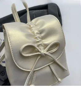 Gros plan du mini sac à dos plissé style ballet avec nœud et finition nacrée métallisée