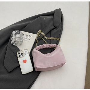 Pink pleated handle handbag with gold chain detail on grey blazer fashion setting