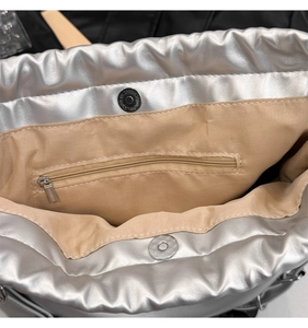 Macro detail of silver bucket bag interior with fabric lining and metal zipper pocket