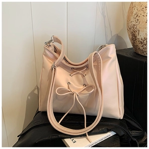 Close-up of the elegant bow detail and crossover lace straps on the cream shoulder bag