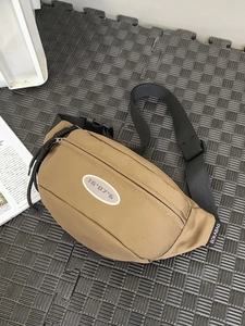 Sac bandoulière minimaliste aux tons terre avec sangle réglable et emblème sport