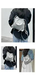 Close-up of silver drawstring bucket bag with metallic bow and chain straps