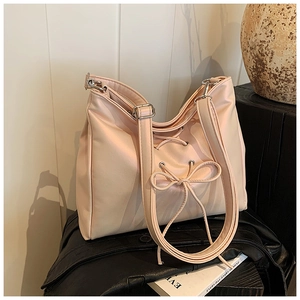 Detail of pink ballet-style shoulder bag with drawstring bow and silver hardware accents