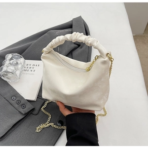Detail of white pleated cloud bag with gold chain strap and metal zipper closure