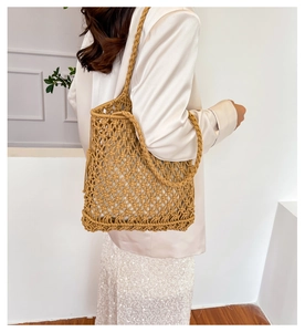 Bohemian hollow woven tote bag in camel color shown with dual straps on model