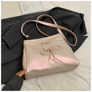 Detail of ballet style shoulder bag with bow tie ribbon and pearly pink metallic finish