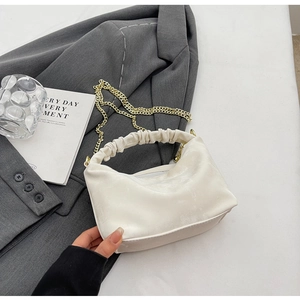 Detail of off-white pleated handle bag on grey blazer with gold chain strap accessory