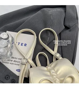 Détail de la boucle argentée réglable et texture plissée sur un mini sac blanc perle
