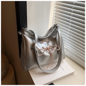 Close-up of metallic silver shoulder bag with pink ribbon bow detail in sunlight