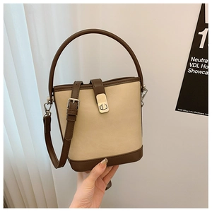 Detail of the golden metal lock and leather strap on a cream and brown bucket bag