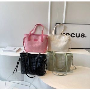 Detail view of woven leather tote bags in pink, beige, black, and green on display