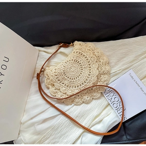 Macro detail of beige crochet shoulder bag with lace knit pattern and brown leather strap