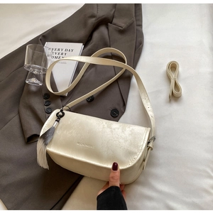 Detail of cream leather shoulder bag with tree print and gradient tassel on a suit
