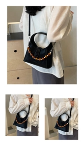 Detail of black trapezoid crossbody bag with amber beaded chain and smooth faux leather finish