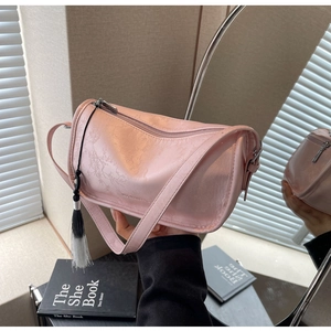 Detailed view of pink textured leather bag with long tassels and mirror reflection