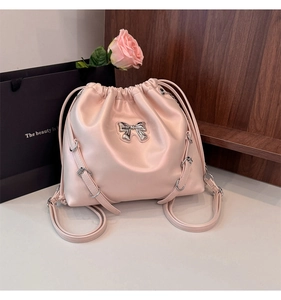 Detailed view of pink drawstring bucket backpack with silver bow hardware and soft leather