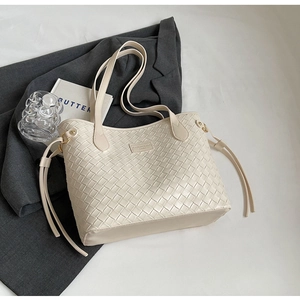 Detail of minimalist tote bag with woven texture, side tassels, and neutral cream finish