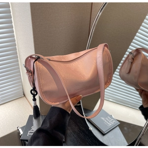 Detail of light pink hobo bag with glossy leather finish and black-white tassel accessory