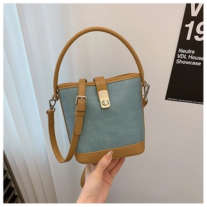 Close-up of contrast leather bucket bag featuring a blue body and brown vintage handle