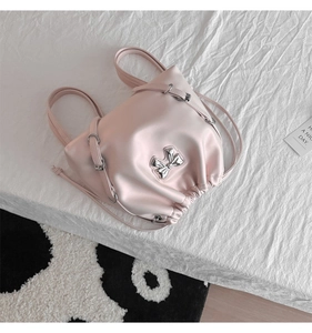 Detail of pink drawstring backpack with silver metal bow and soft leather texture