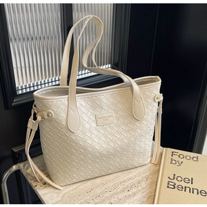 Detail of cream woven tote bag with cross-stitch pattern on marble surface
