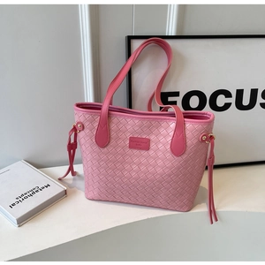Close-up of pink woven tote bag showing large plaid texture and fringe detail