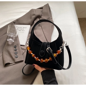 Detail of black suede hobo bag with chunky amber beaded chain and leather shoulder strap