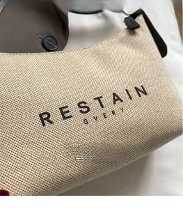 Gros plan sur le sac croissant en tissu beige avec bandoulière en cuir noir et logo