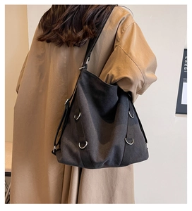 Detailansicht einer großen schwarzen Canvas-Tasche, getragen mit einem Trenchcoat
