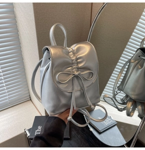 Détail d'un sac à dos argenté métallisé plissé avec nœuds reflété dans un miroir élégant