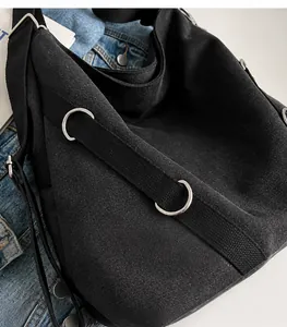 Detail einer schwarzen Segeltuchtasche mit silbernen Metallteilen auf Denim